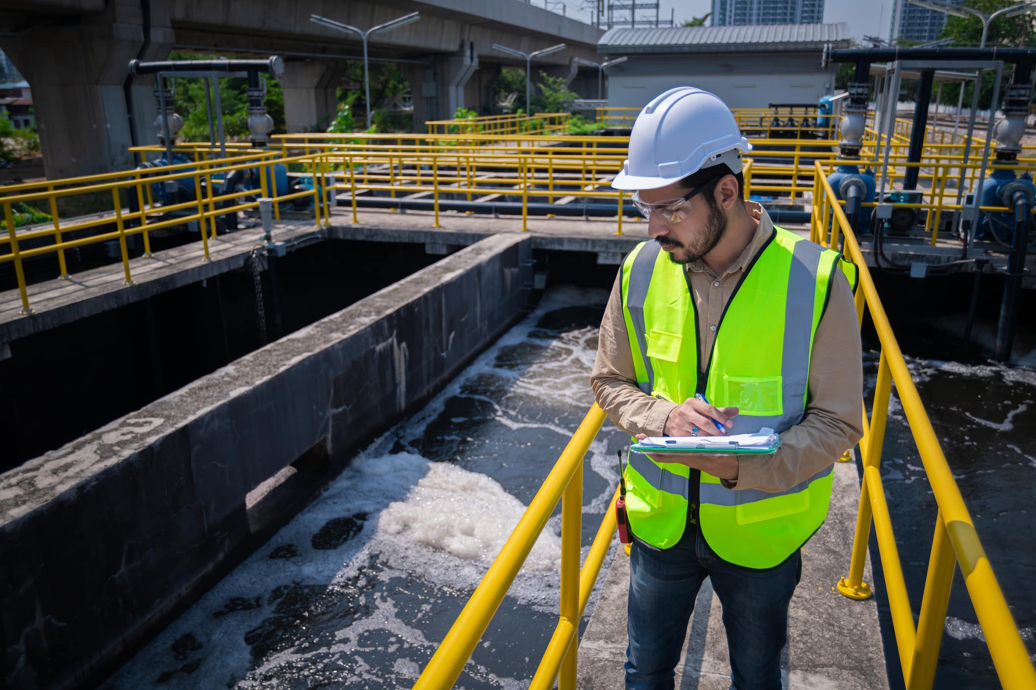 VA-projektör i gul arbetsväst kontrollerar vatten och avfall projekt på arbetsplats